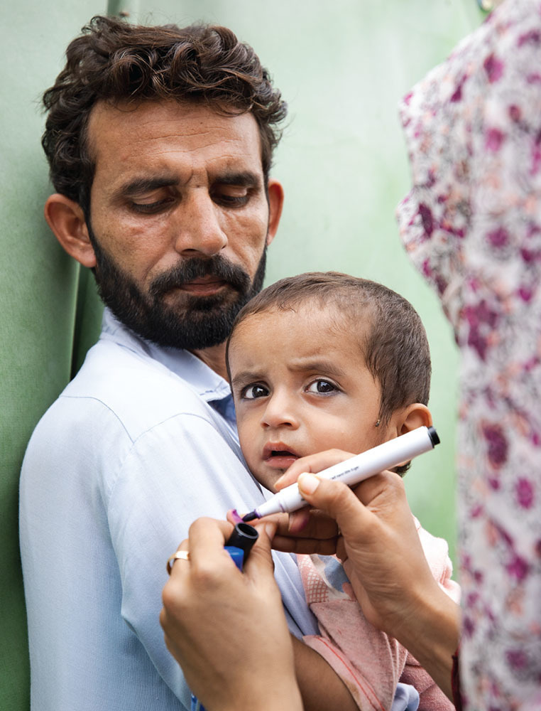 a polio vaccinator marks a child